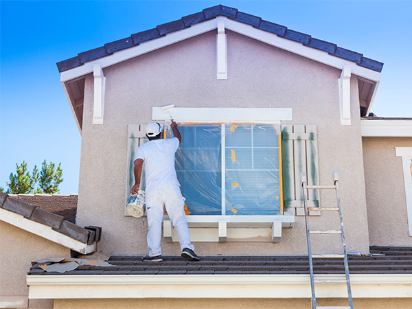 Home remodeling contractor near Agoura Hills painting the exterior of upstairs bedroom windows.